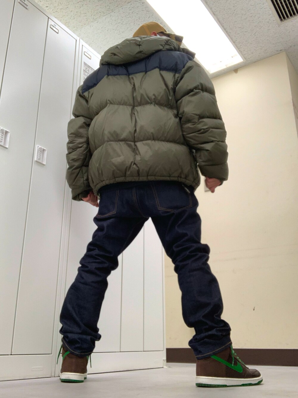 グリーン系のダウンジャケット/コート、ブルー系のデニムパンツ、ブラウン系のスニーカーを着用したメンズの冬コーディネートの2枚目の写真