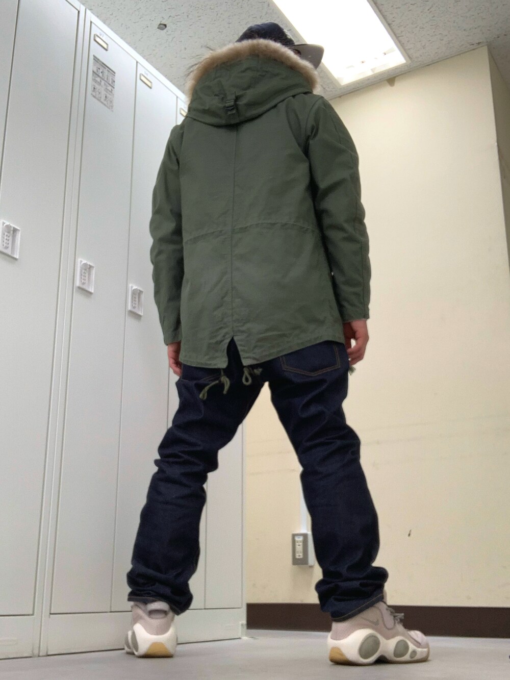 グリーン系のモッズコート、ブルー系のデニムパンツ、ピンク系のスニーカーを着用したメンズの秋コーディネートの2枚目の写真