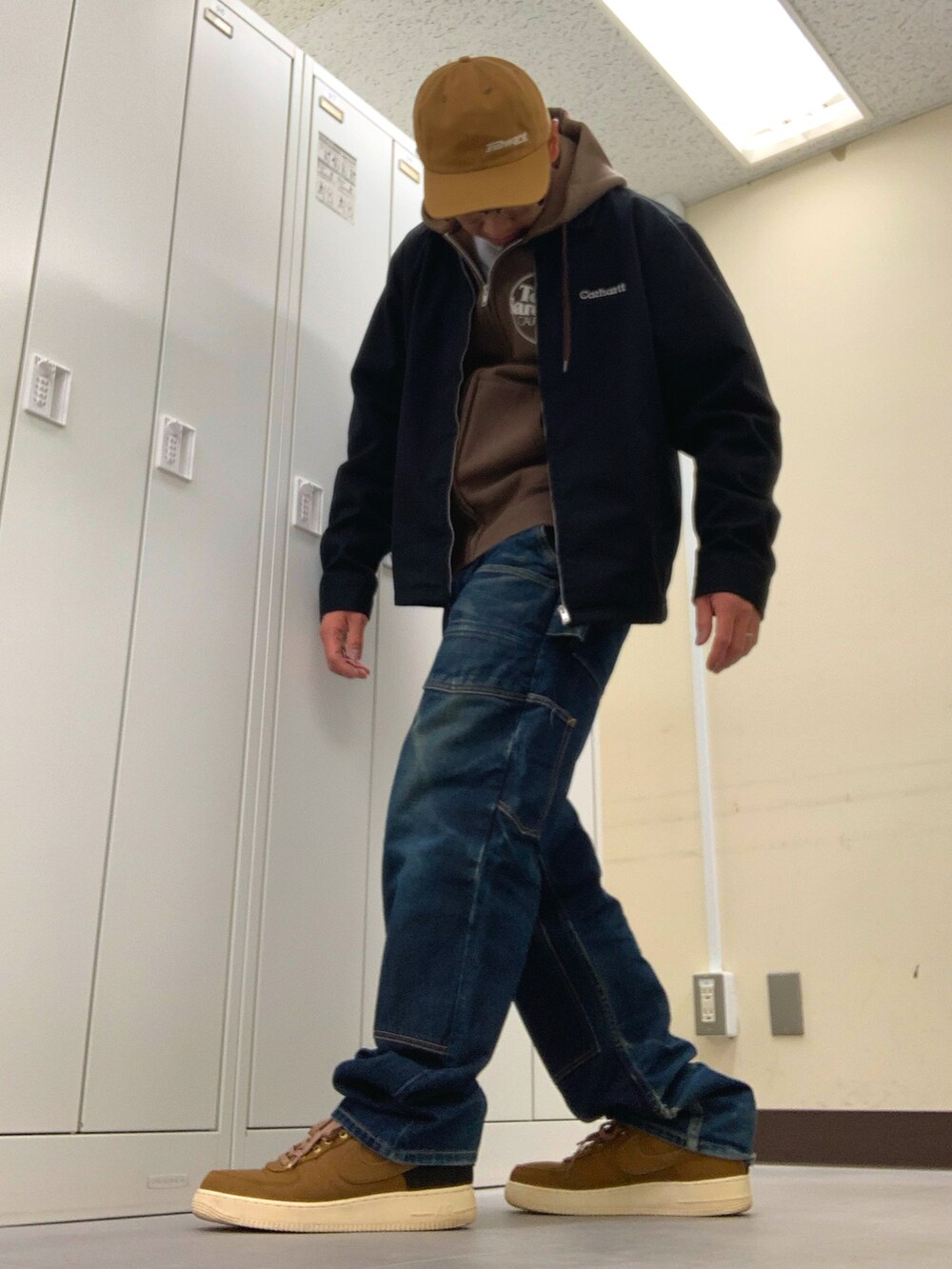 ブラウン系のパーカー、ブラック系のブルゾン、ブルー系のデニムパンツを着用したメンズの秋コーディネートの2枚目の写真