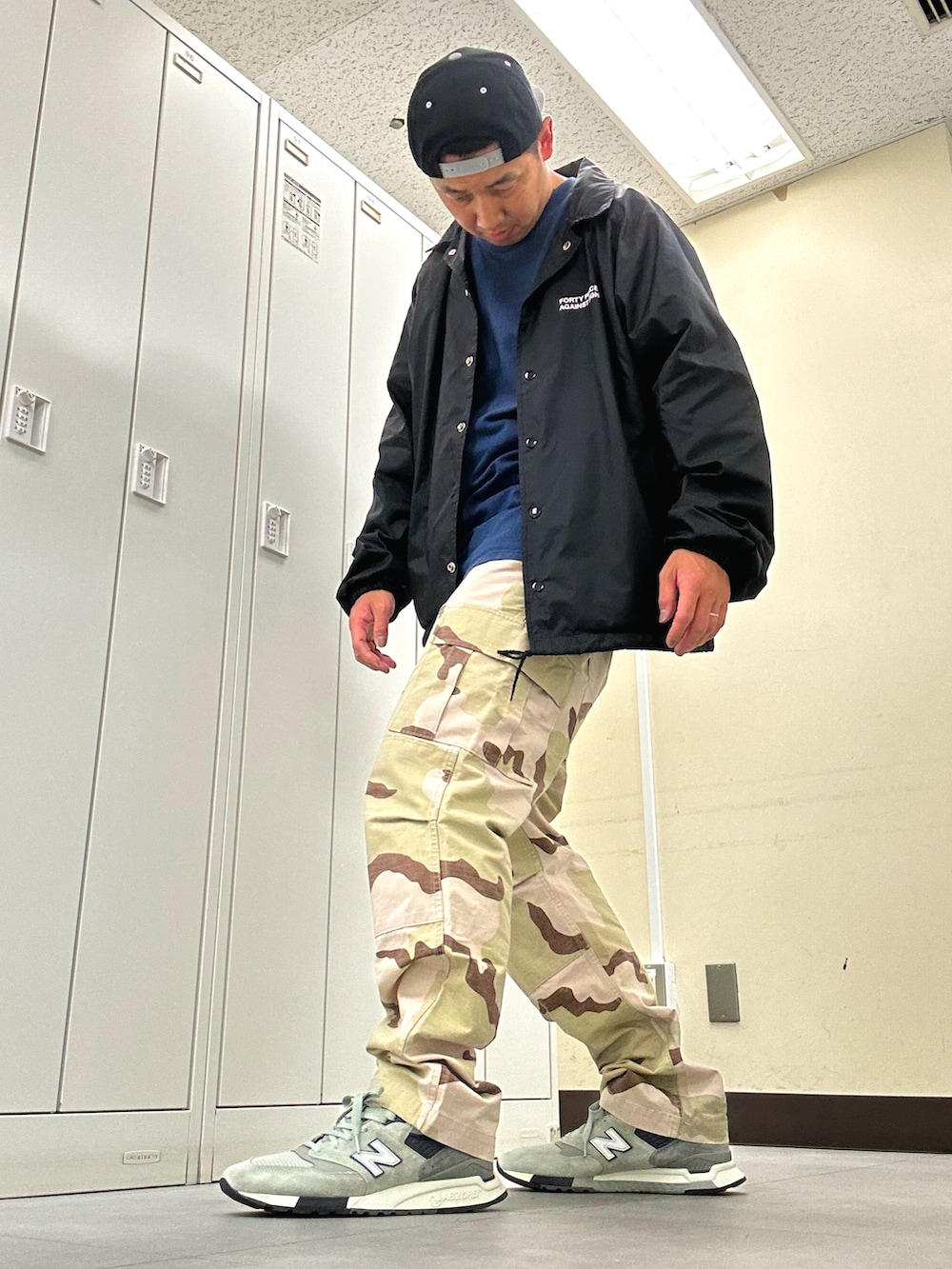 ブラック系のナイロンジャケット、ベージュ系のカーゴパンツ、グレー系のスニーカーを着用したメンズの春コーディネートの2枚目の写真