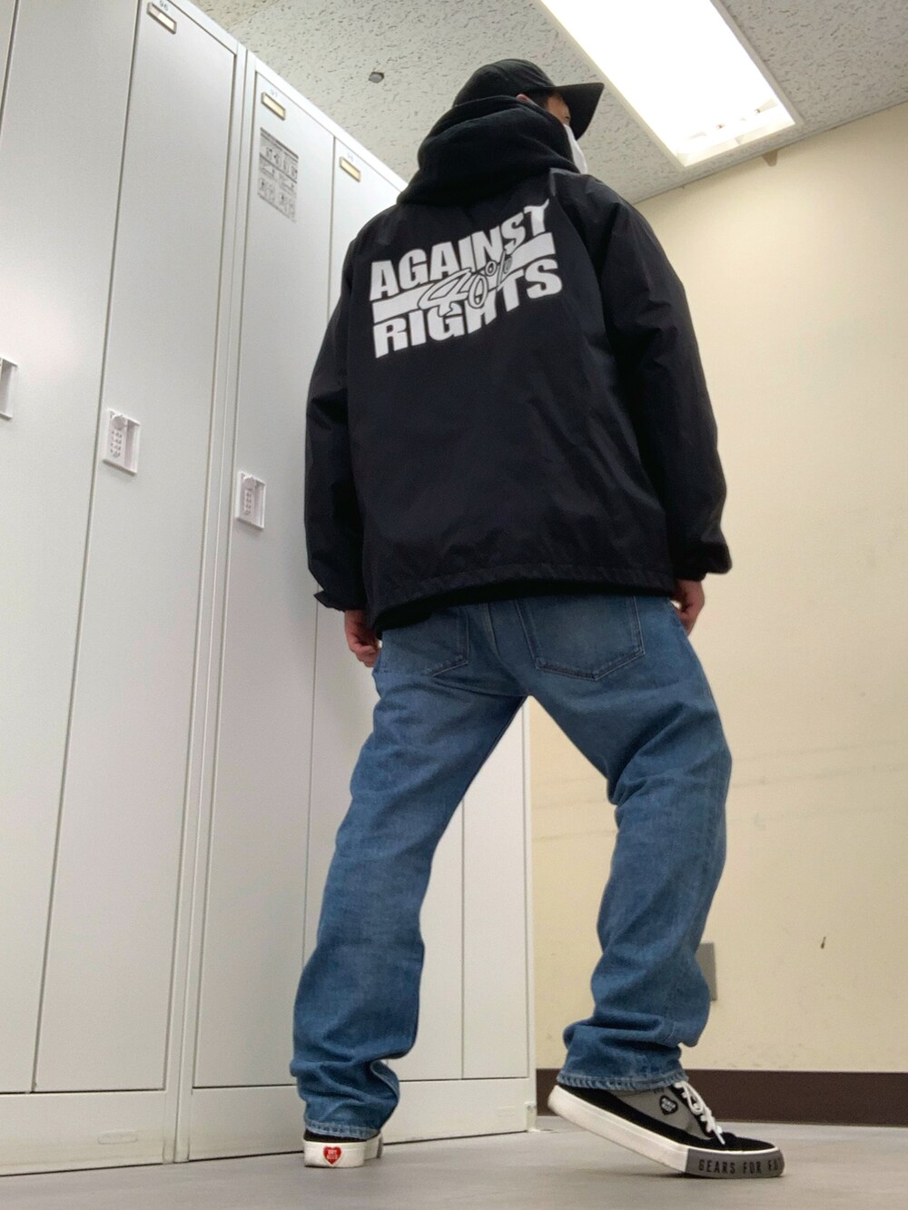 ブラック系のパーカー、ブラック系のナイロンジャケット、ブルー系のデニムパンツを着用したメンズの春コーディネートの3枚目の写真