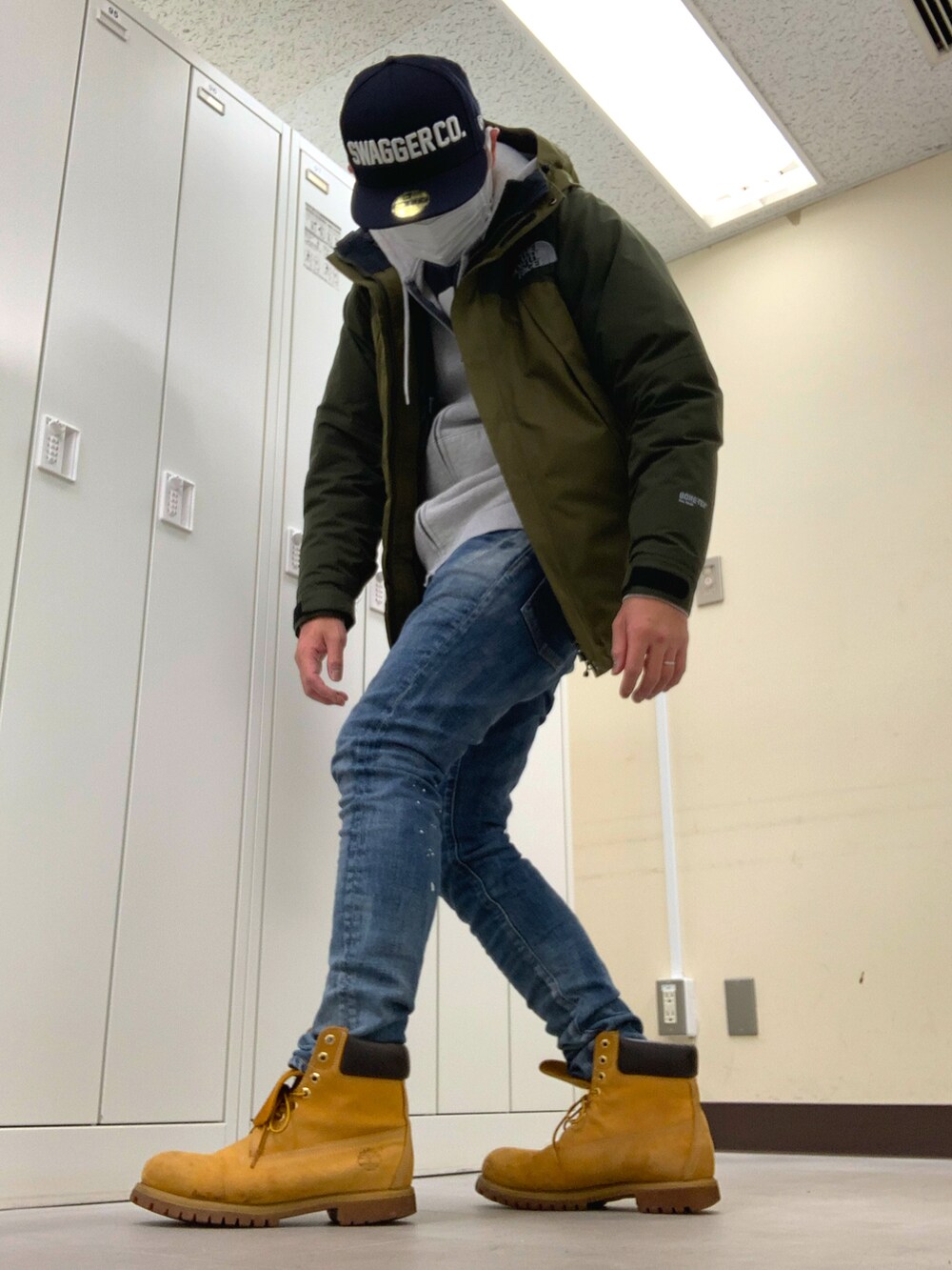 グリーン系のマウンテンパーカー、ブルー系のデニムパンツ、イエロー系のブーツを着用したメンズの冬コーディネートの2枚目の写真