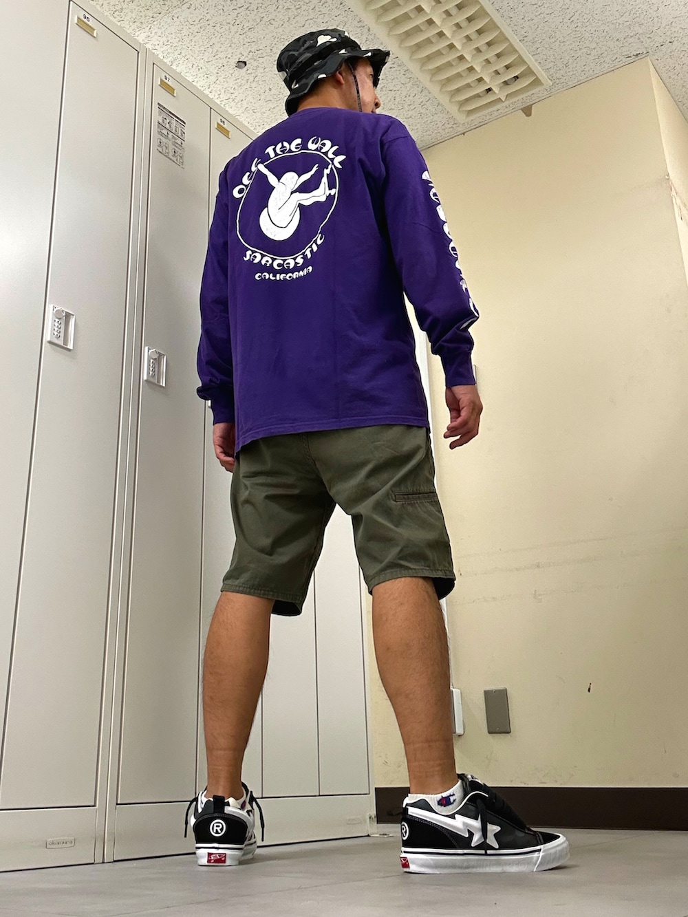 パープル系のTシャツ/カットソー、グリーン系のチノパンツ、ブラック系のスニーカーを着用したメンズの秋コーディネートの3枚目の写真