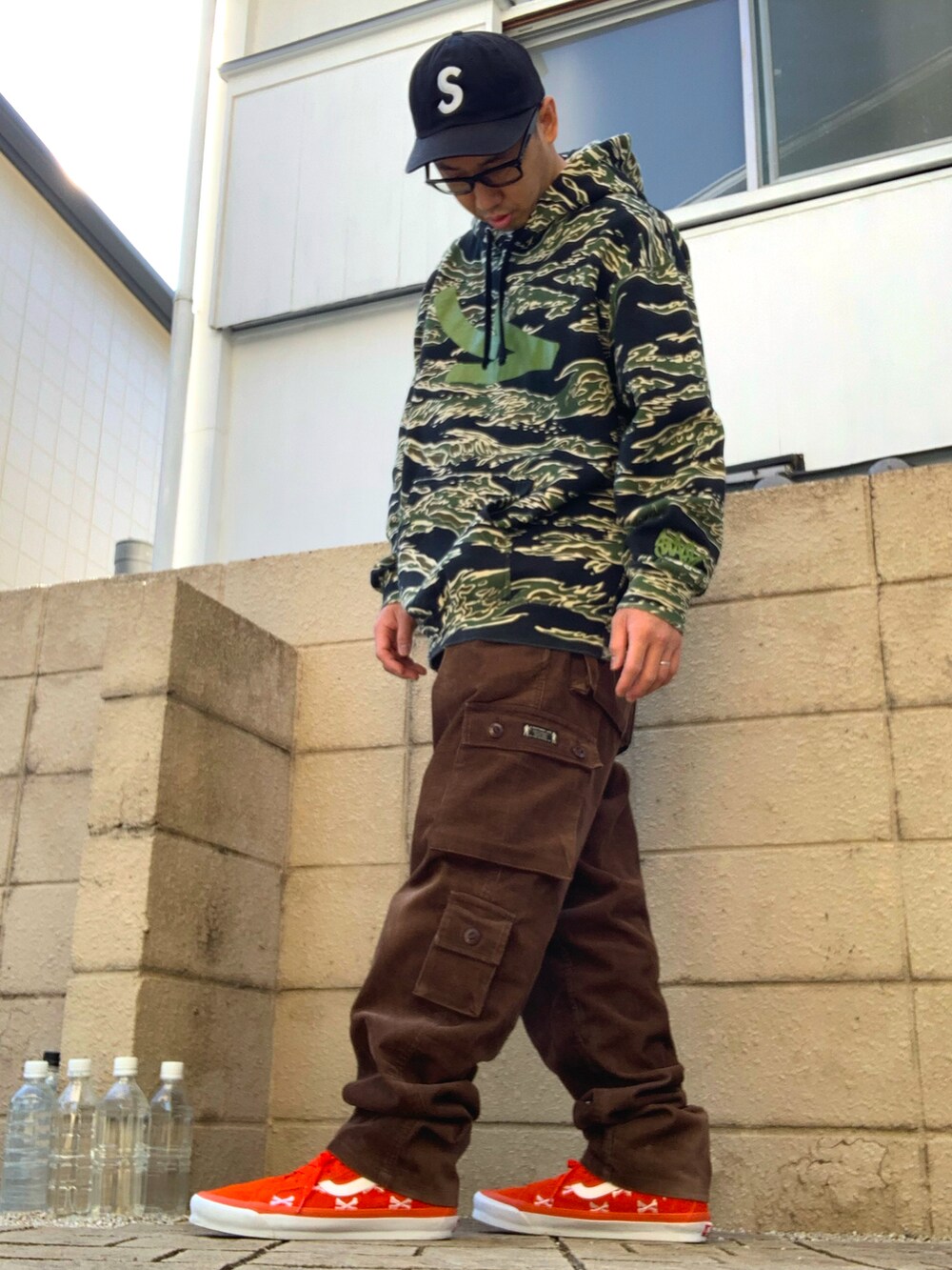 グリーン系のパーカー、ブラウン系のカーゴパンツ、オレンジ系のスニーカーを着用したメンズの秋コーディネートの2枚目の写真