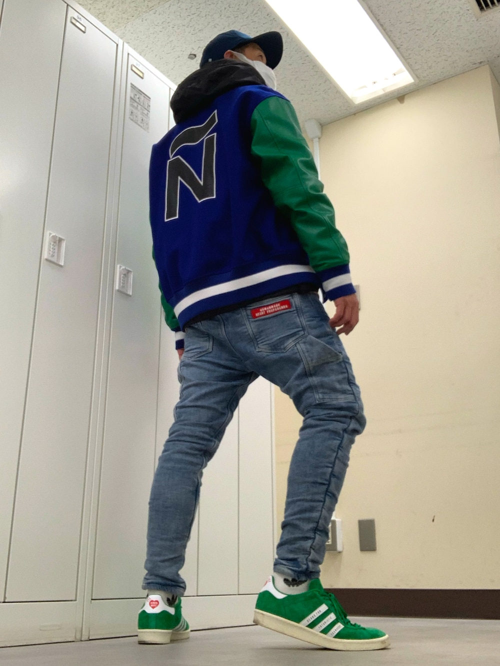 ブルー系のスタジャン、ブラック系のマウンテンパーカー、ブルー系のデニムパンツを着用したメンズの春コーディネートの3枚目の写真