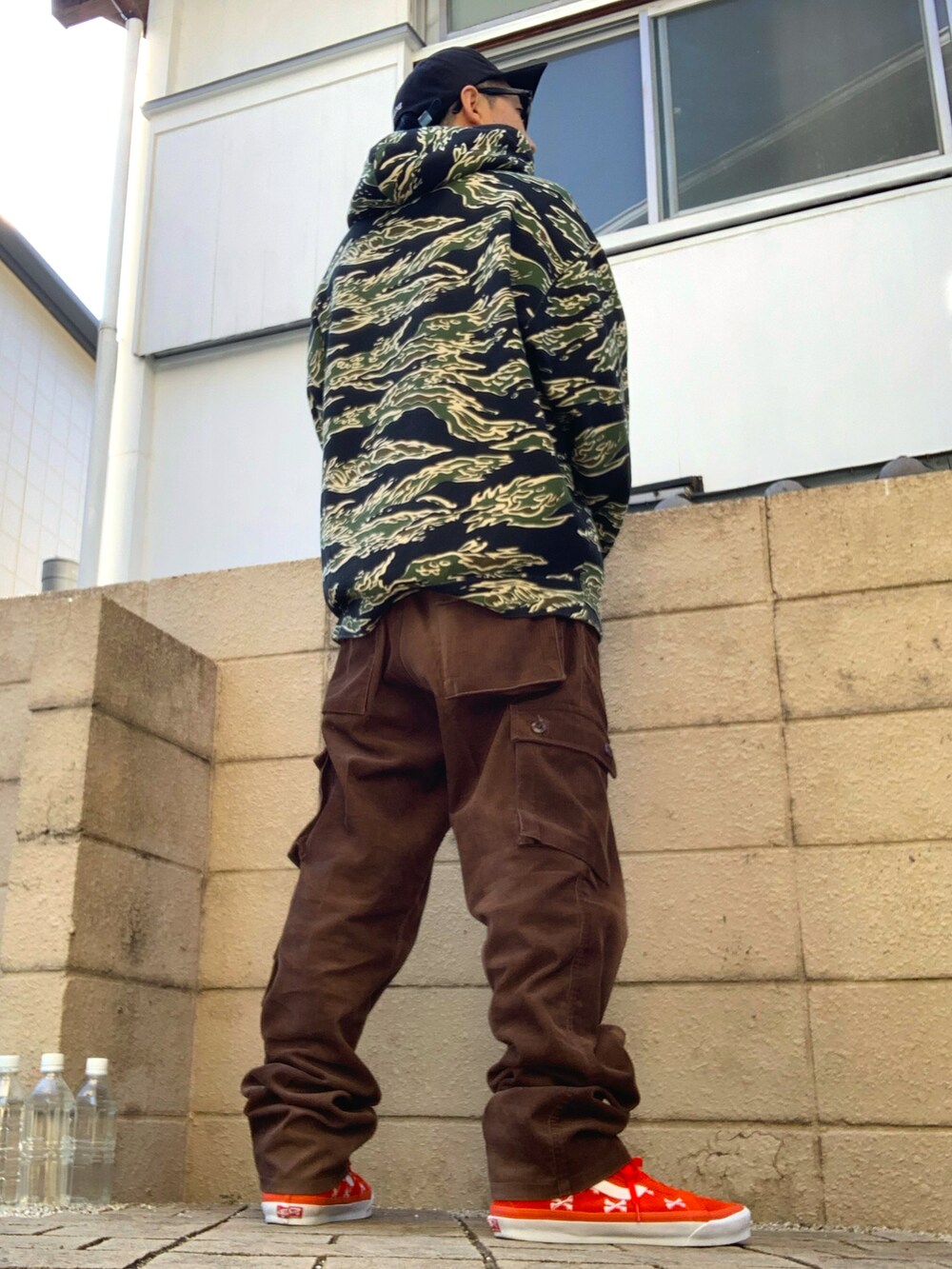 グリーン系のパーカー、ブラウン系のカーゴパンツ、オレンジ系のスニーカーを着用したメンズの秋コーディネートの3枚目の写真