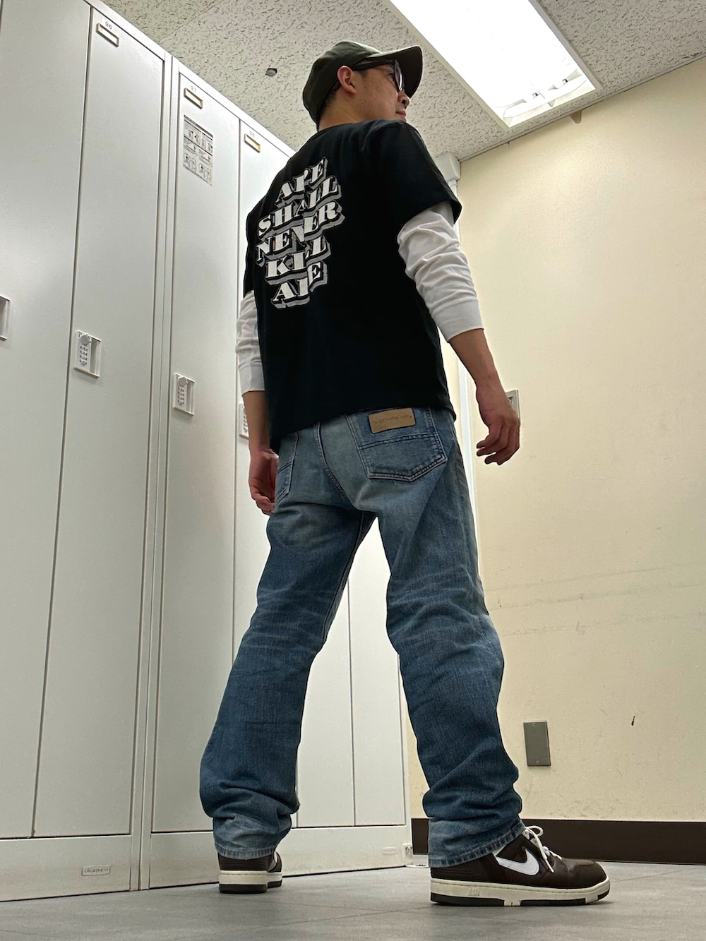 ブラック系のTシャツ/カットソー、ブルー系のデニムパンツ、ブラウン系のスニーカーを着用したメンズの春コーディネートの3枚目の写真