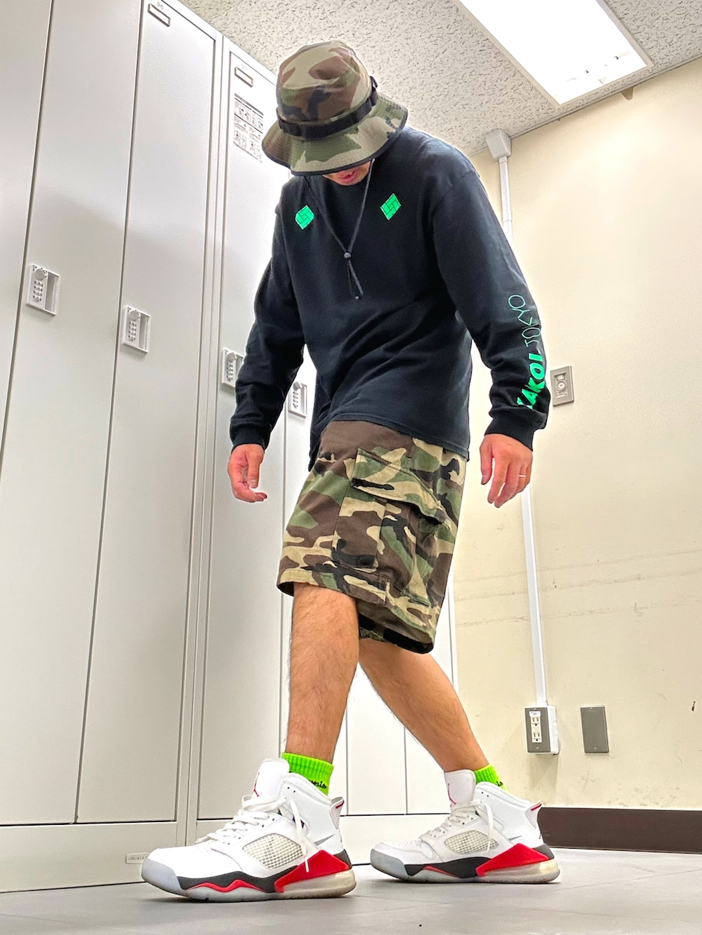 ブラック系のTシャツ/カットソー、グリーン系のカーゴパンツ、ホワイト系のスニーカーを着用したメンズの秋コーディネートの2枚目の写真