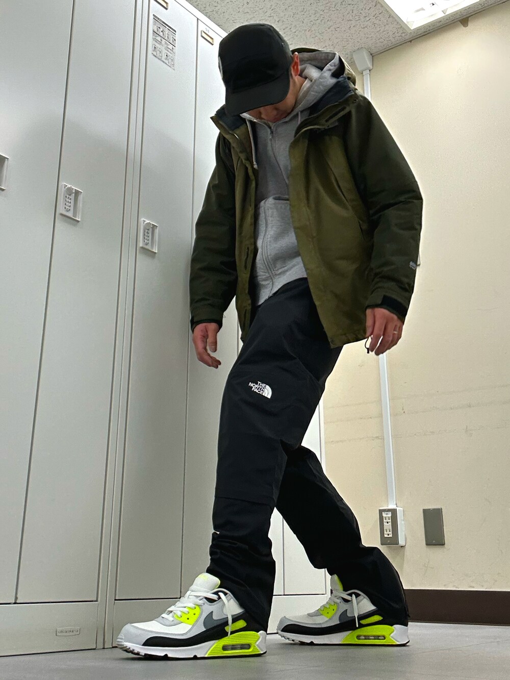 グリーン系のマウンテンパーカー、ブラック系のその他パンツ、ホワイト系のスニーカーを着用したメンズの秋コーディネートの2枚目の写真