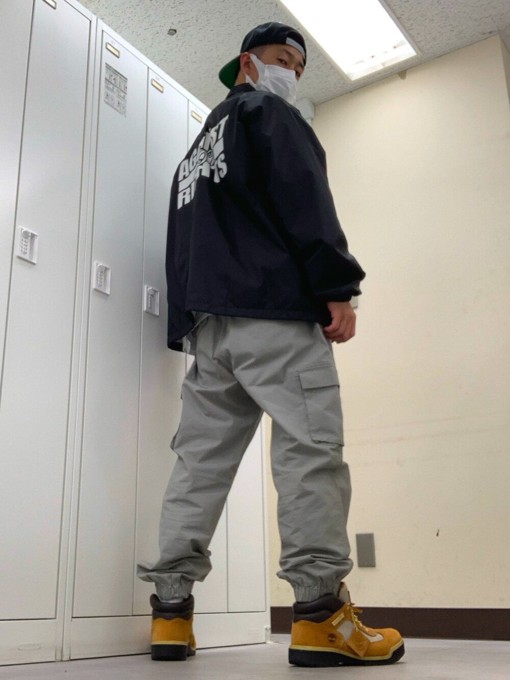 ブラック系のナイロンジャケット、グレー系のカーゴパンツ、ベージュ系のブーツを着用したメンズの春コーディネートの3枚目の写真