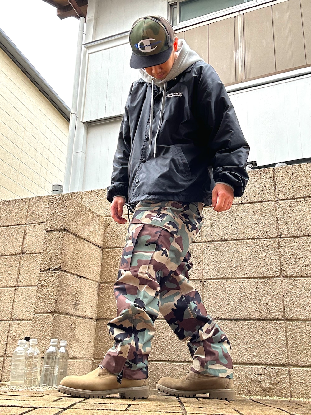 ブラック系のナイロンジャケット、グリーン系のカーゴパンツ、ベージュ系のブーツを着用したメンズの春コーディネートの2枚目の写真