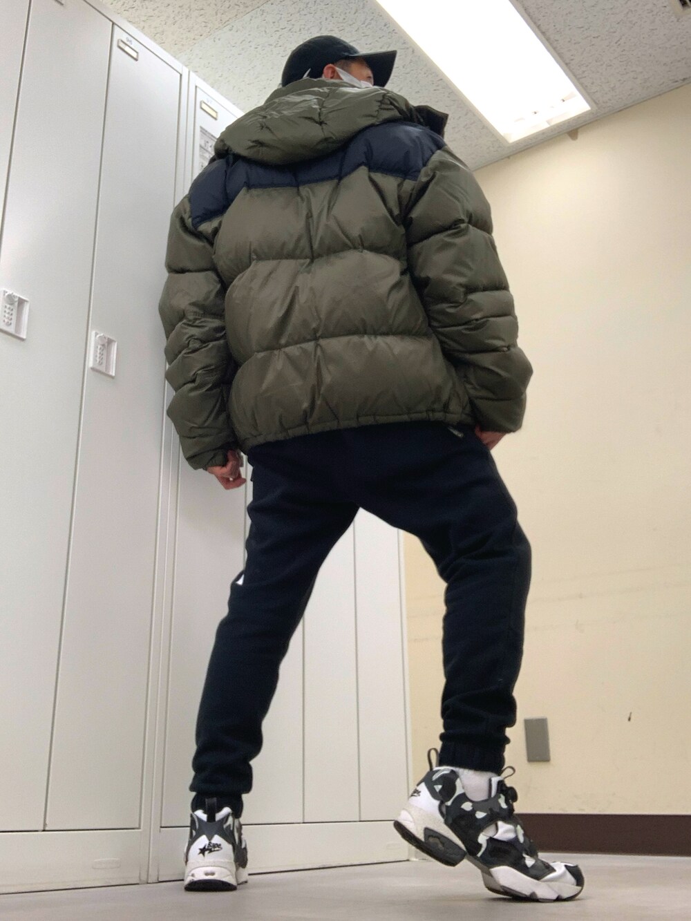 グリーン系のダウンジャケット/コート、パープル系のTシャツ/カットソー、ブラック系のスウェットパンツを着用したメンズの冬コーディネートの3枚目の写真