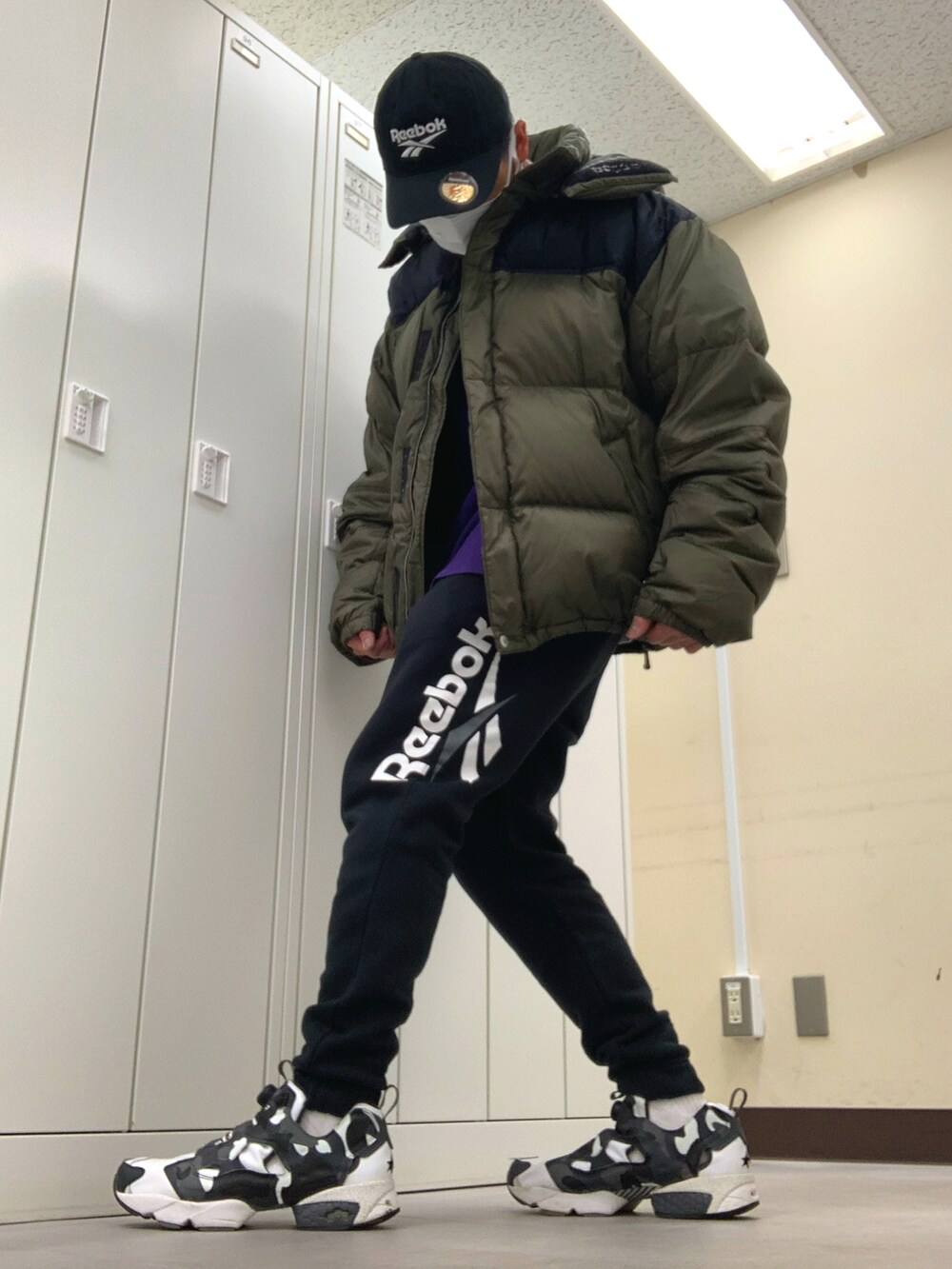 グリーン系のダウンジャケット/コート、パープル系のTシャツ/カットソー、ブラック系のスウェットパンツを着用したメンズの冬コーディネートの2枚目の写真