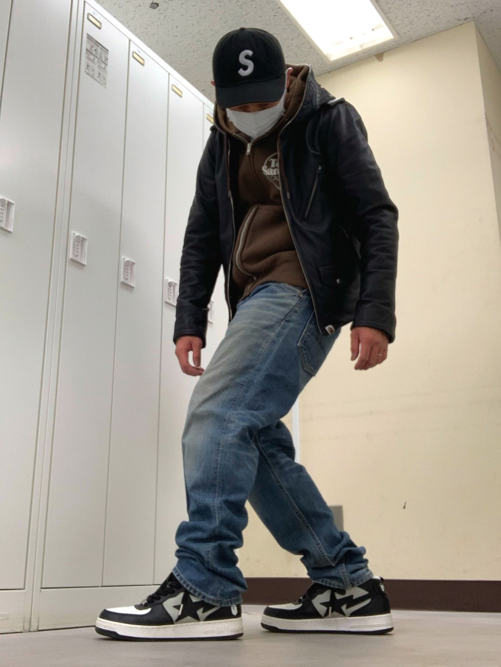 ブラウン系のパーカー、ブラック系のその他アウター、ブルー系のデニムパンツを着用したメンズの冬コーディネートの2枚目の写真