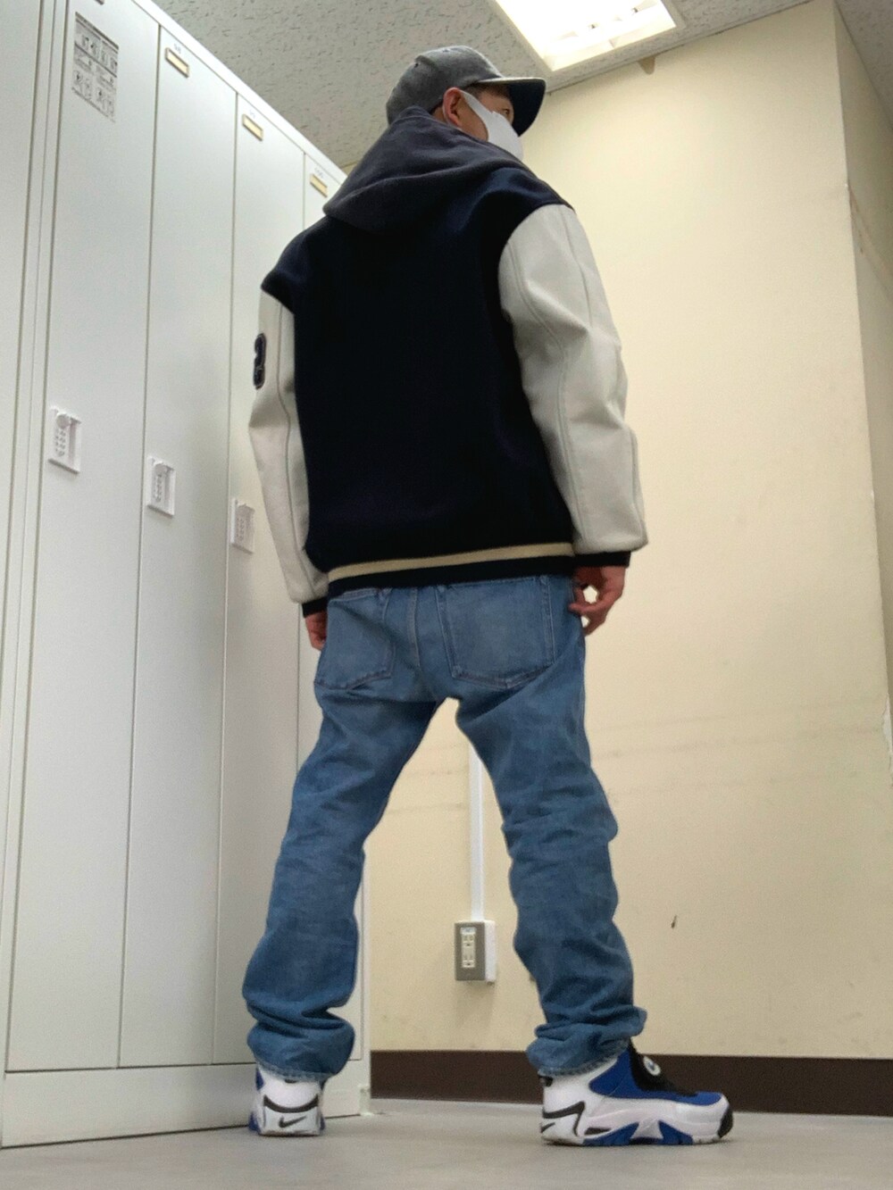 オレンジ系のTシャツ/カットソー、ブルー系のデニムパンツ、ブルー系のスニーカーを着用したメンズの冬コーディネートの2枚目の写真