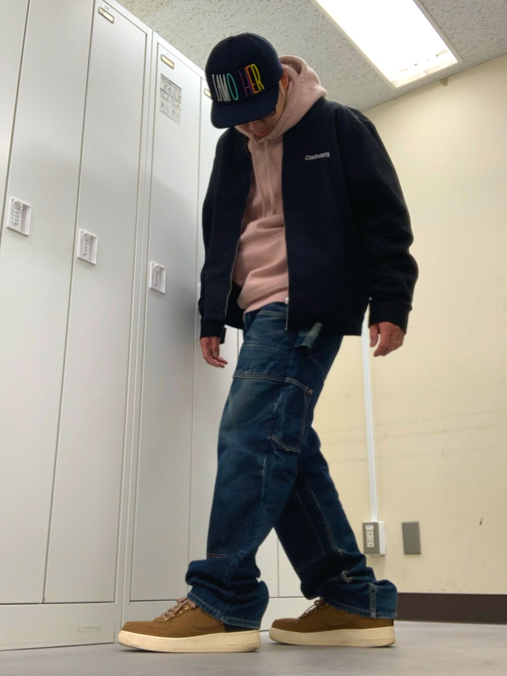 ピンク系のパーカー、ブラック系のブルゾン、ブルー系のデニムパンツを着用したメンズの秋コーディネートの2枚目の写真