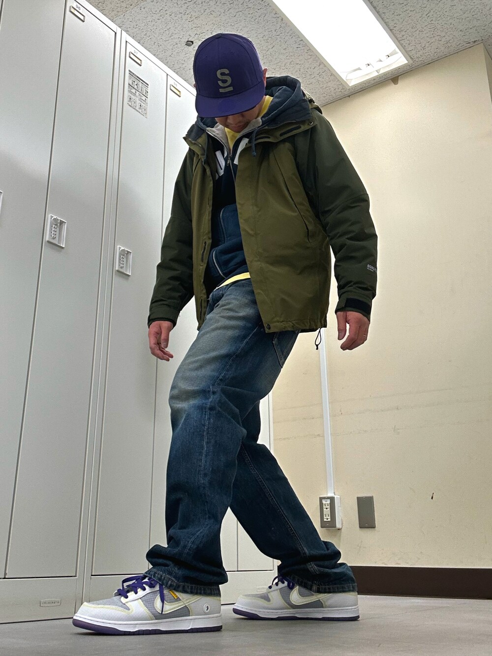 ブルー系のパーカー、グリーン系のマウンテンパーカー、ブルー系のデニムパンツを着用したメンズの春コーディネートの2枚目の写真