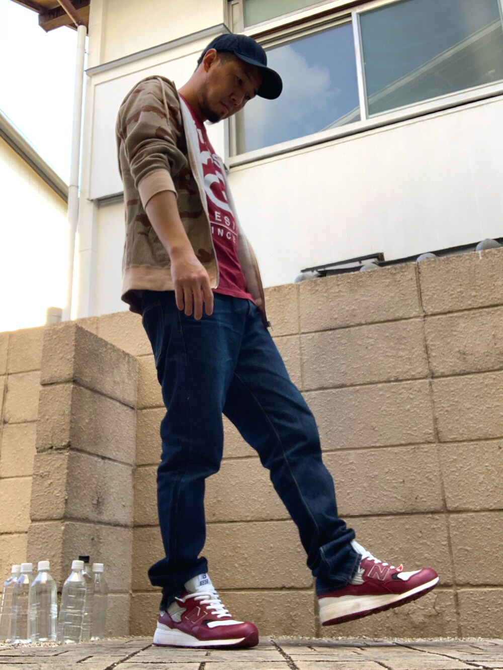 レッド系のTシャツ/カットソー、ベージュ系のパーカー、ブルー系のデニムパンツを着用したメンズの秋コーディネートの2枚目の写真