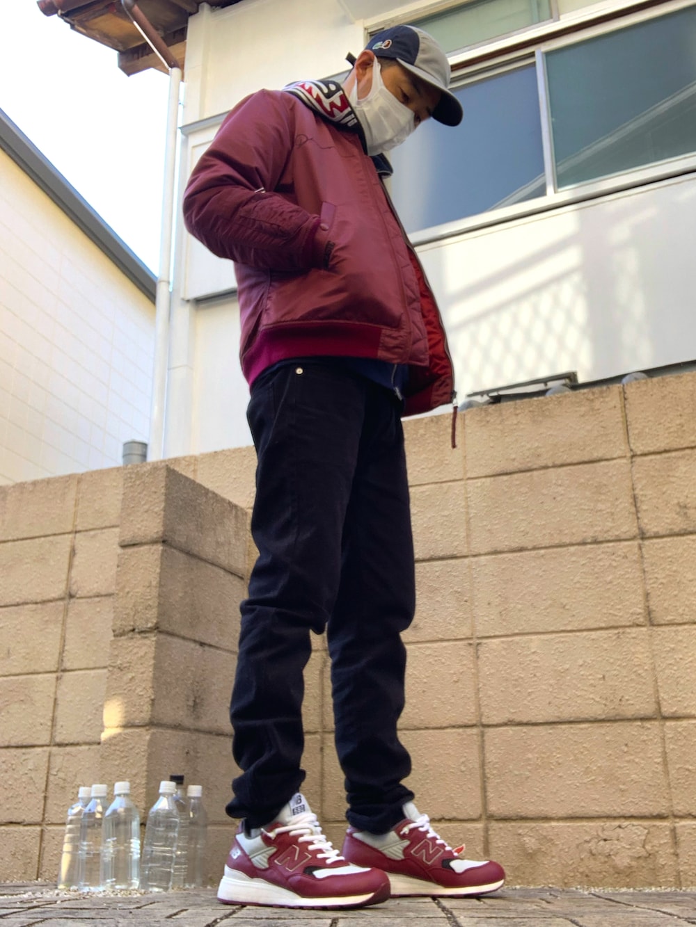 レッド系のミリタリージャケット、ブラック系のデニムパンツ、ブルー系のパーカーを着用したメンズの秋コーディネートの2枚目の写真