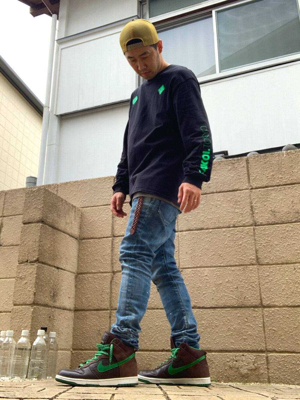 ブラック系のTシャツ/カットソー、ブルー系のデニムパンツ、ブラウン系のスニーカーを着用したメンズの夏コーディネートの2枚目の写真