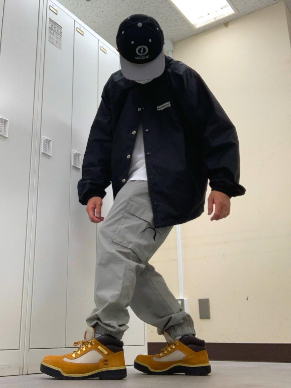 ブラック系のナイロンジャケット、グレー系のカーゴパンツ、ベージュ系のブーツを着用したメンズの春コーディネートの2枚目の写真