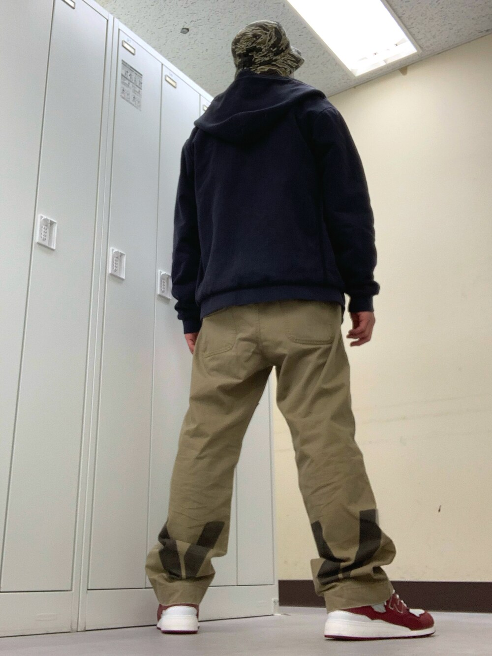 レッド系のTシャツ/カットソー、ブルー系のパーカー、ベージュ系のチノパンツを着用したメンズの秋コーディネートの2枚目の写真