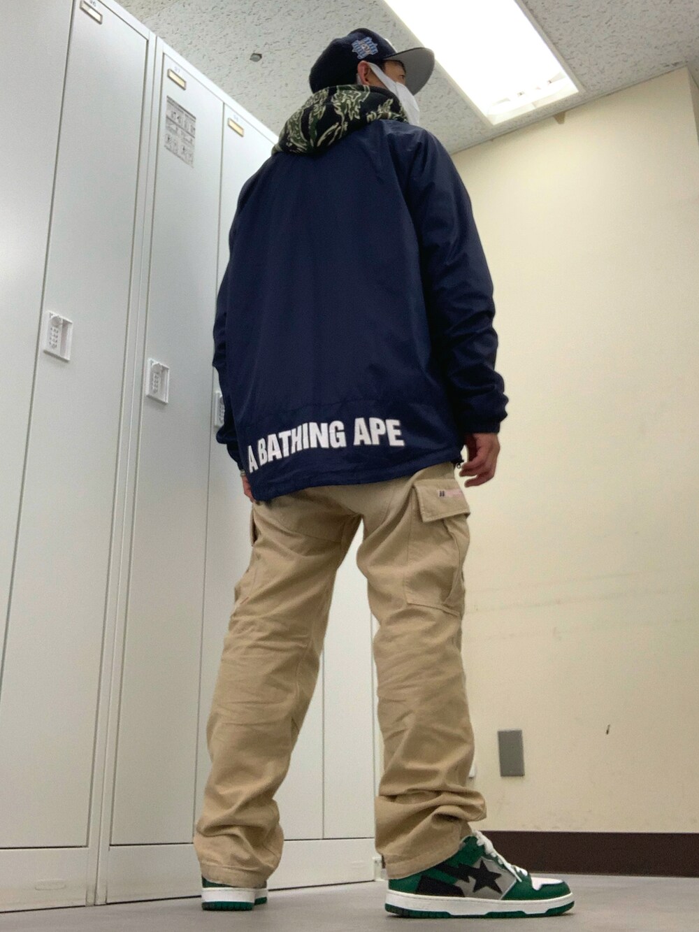 ブルー系のナイロンジャケット、グリーン系のパーカー、ベージュ系のカーゴパンツを着用したメンズの春コーディネートの3枚目の写真