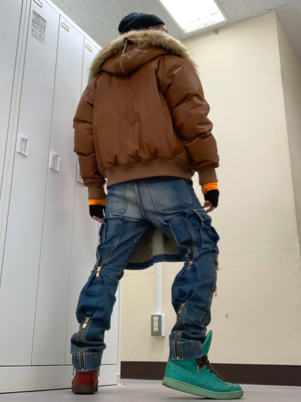 ブラウン系のミリタリージャケット、ブルー系のデニムパンツ、その他のスニーカーを着用したメンズの冬コーディネートの3枚目の写真