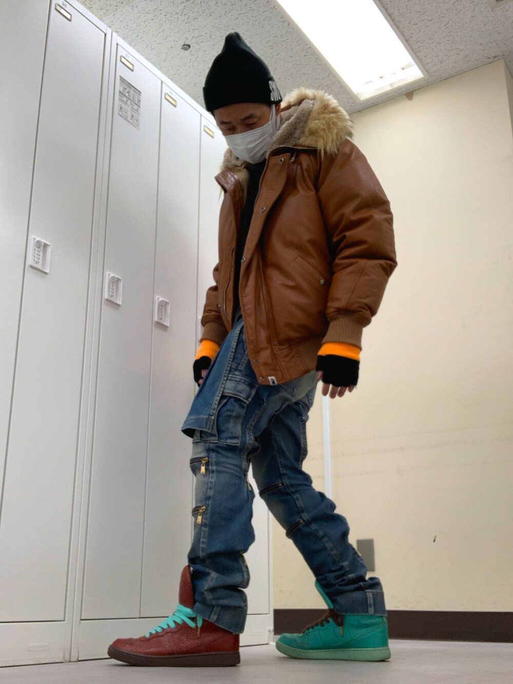 ブラウン系のミリタリージャケット、ブルー系のデニムパンツ、その他のスニーカーを着用したメンズの冬コーディネートの2枚目の写真