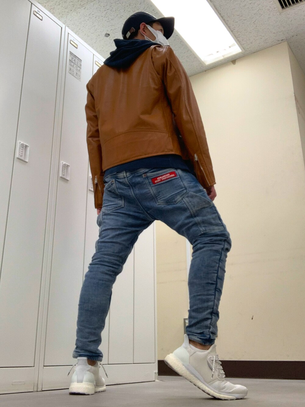 ブラウン系のライダースジャケット、ブルー系のデニムパンツ、ホワイト系のスニーカーを着用したメンズの春コーディネートの3枚目の写真