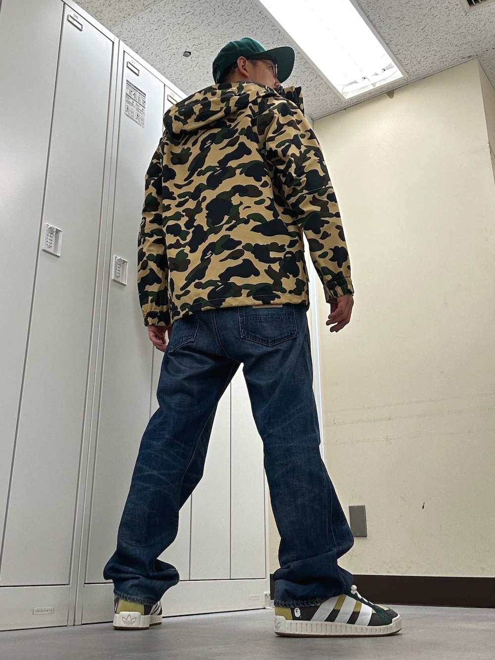 イエロー系のマウンテンパーカー、ブルー系のデニムパンツ、グリーン系のスニーカーを着用したメンズの秋コーディネートの3枚目の写真