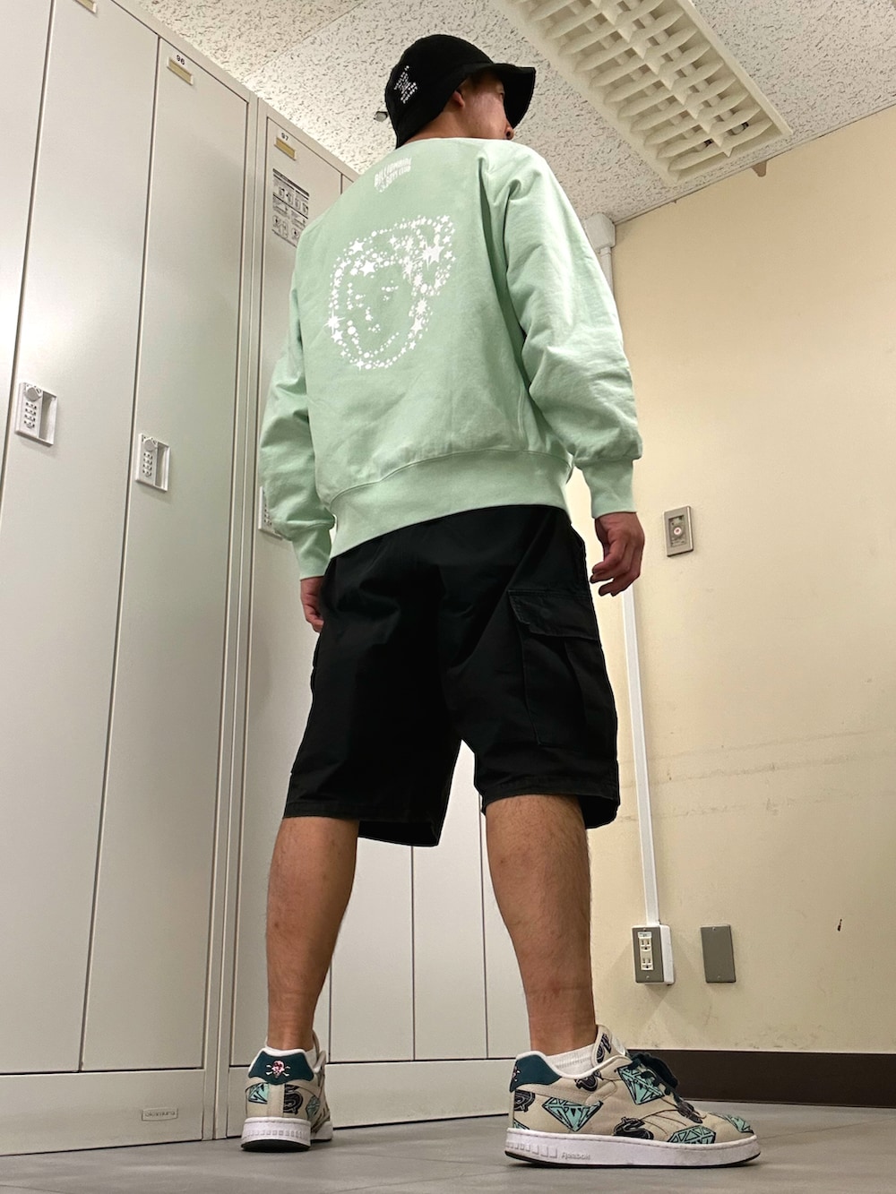 グリーン系のスウェット、ブラック系のカーゴパンツ、ベージュ系のスニーカーを着用したメンズの春コーディネートの3枚目の写真