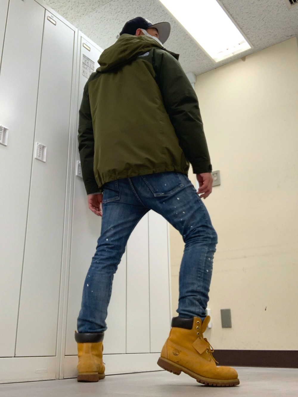 グリーン系のマウンテンパーカー、ブルー系のデニムパンツ、イエロー系のブーツを着用したメンズの冬コーディネートの3枚目の写真