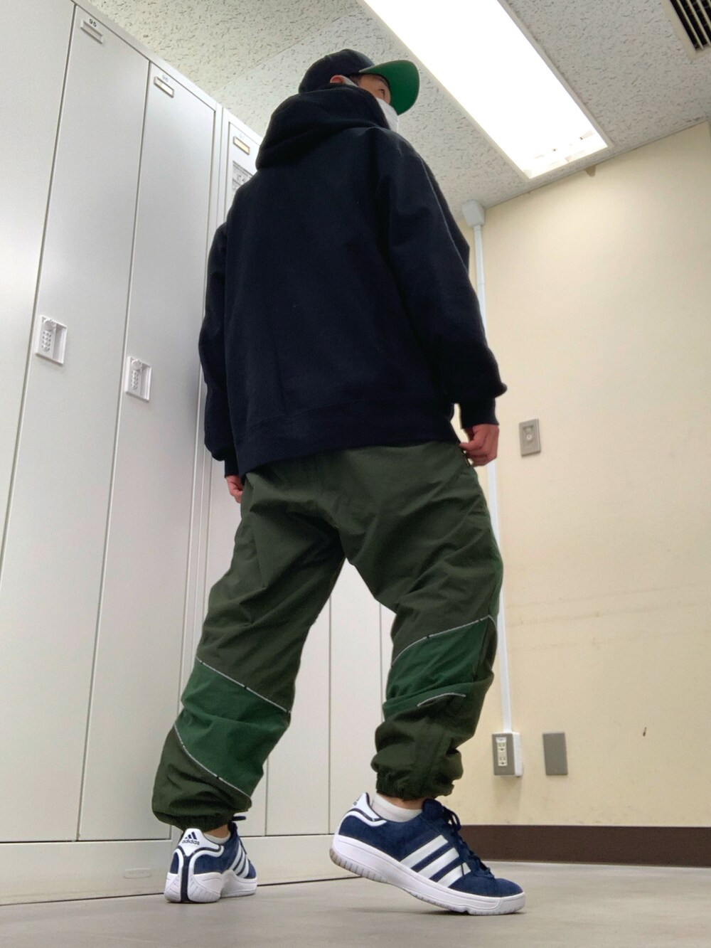 ブラック系のパーカー、グリーン系のその他パンツ、ブルー系のスニーカーを着用したメンズの春コーディネートの3枚目の写真