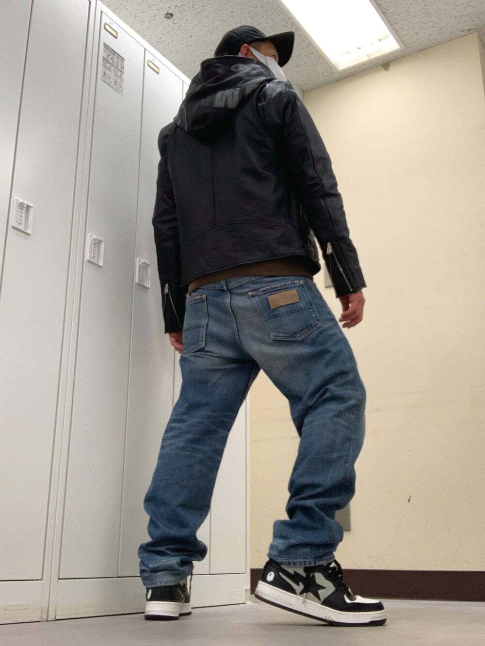 ブラウン系のパーカー、ブラック系のその他アウター、ブルー系のデニムパンツを着用したメンズの冬コーディネートの3枚目の写真