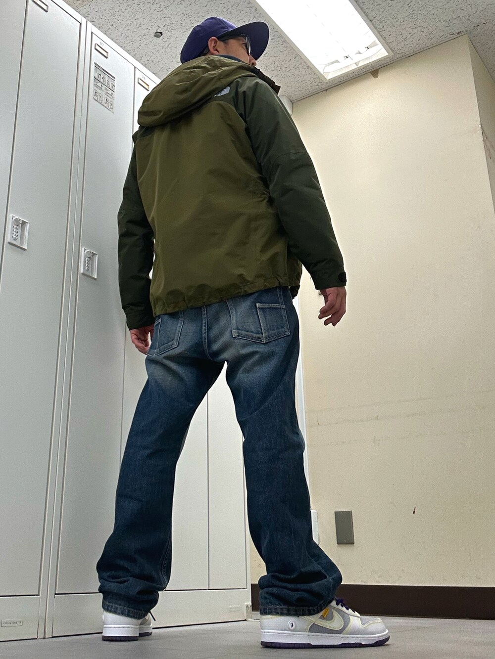 ブルー系のパーカー、グリーン系のマウンテンパーカー、ブルー系のデニムパンツを着用したメンズの春コーディネートの3枚目の写真