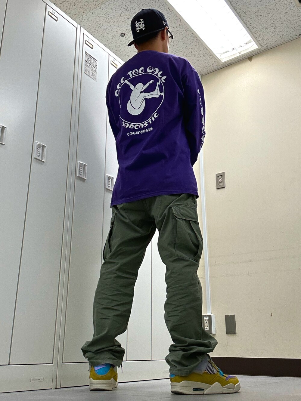 パープル系のTシャツ/カットソー、グリーン系のカーゴパンツ、ベージュ系のスニーカーを着用したメンズの秋コーディネートの3枚目の写真