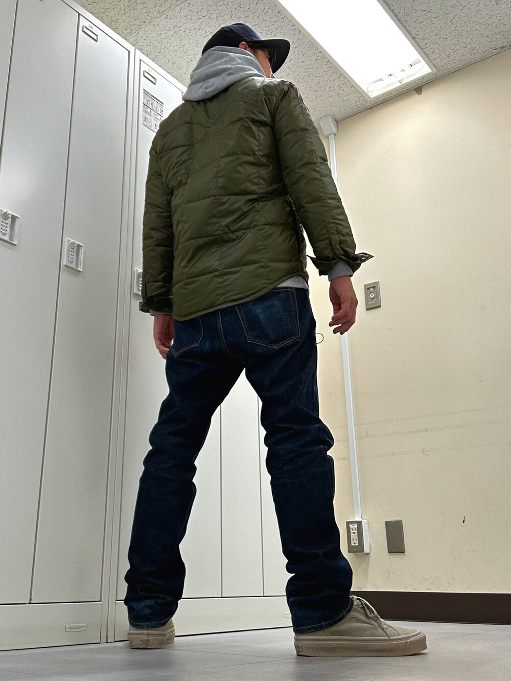 グリーン系のダウンジャケット/コート、ブルー系のデニムパンツ、グレー系のスニーカーを着用したメンズの秋コーディネートの3枚目の写真