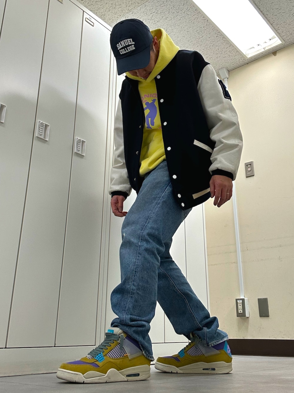 イエロー系のパーカー、ブルー系のスタジャン、ブルー系のデニムパンツを着用したメンズの冬コーディネートの2枚目の写真