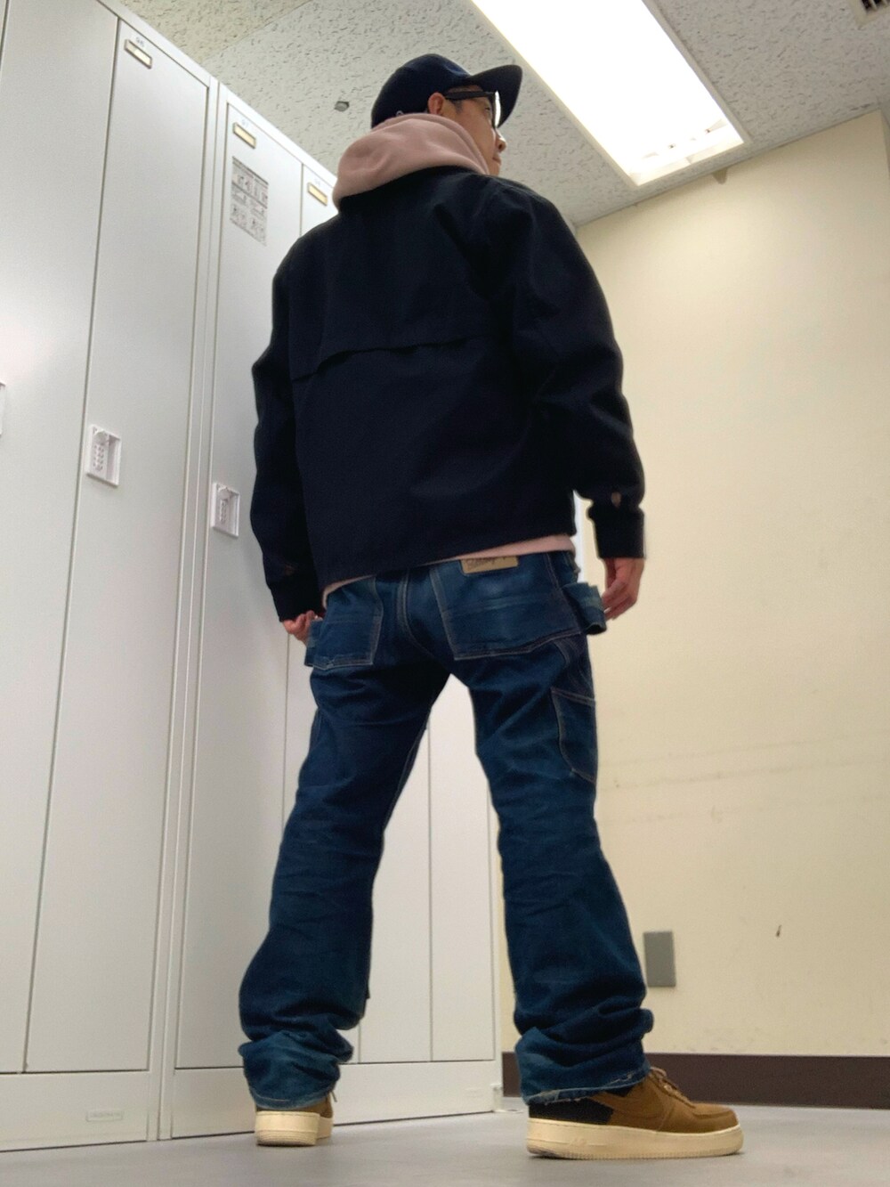 ピンク系のパーカー、ブラック系のブルゾン、ブルー系のデニムパンツを着用したメンズの秋コーディネートの3枚目の写真