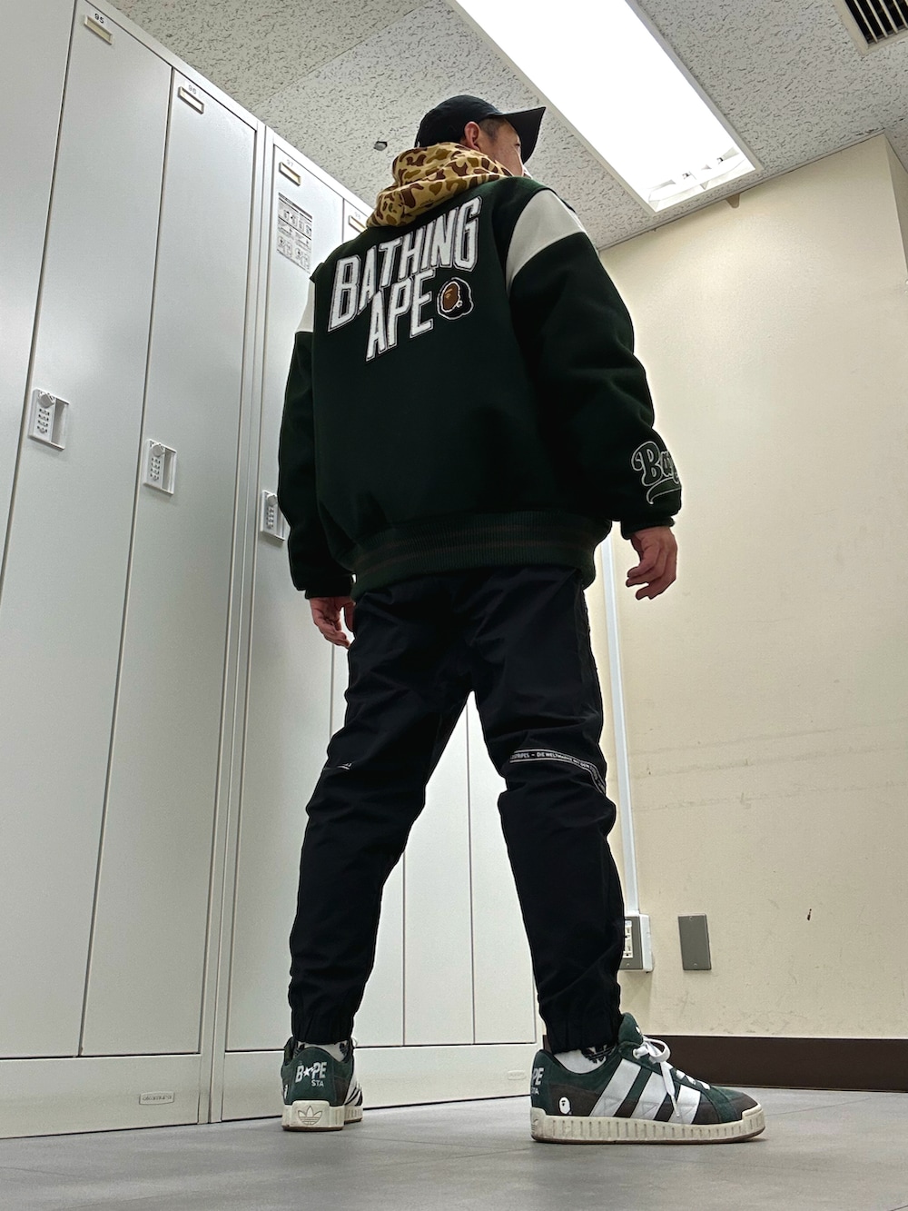 グリーン系のスタジャン、ブラック系のその他パンツ、グリーン系のスニーカーを着用したメンズの冬コーディネートの3枚目の写真