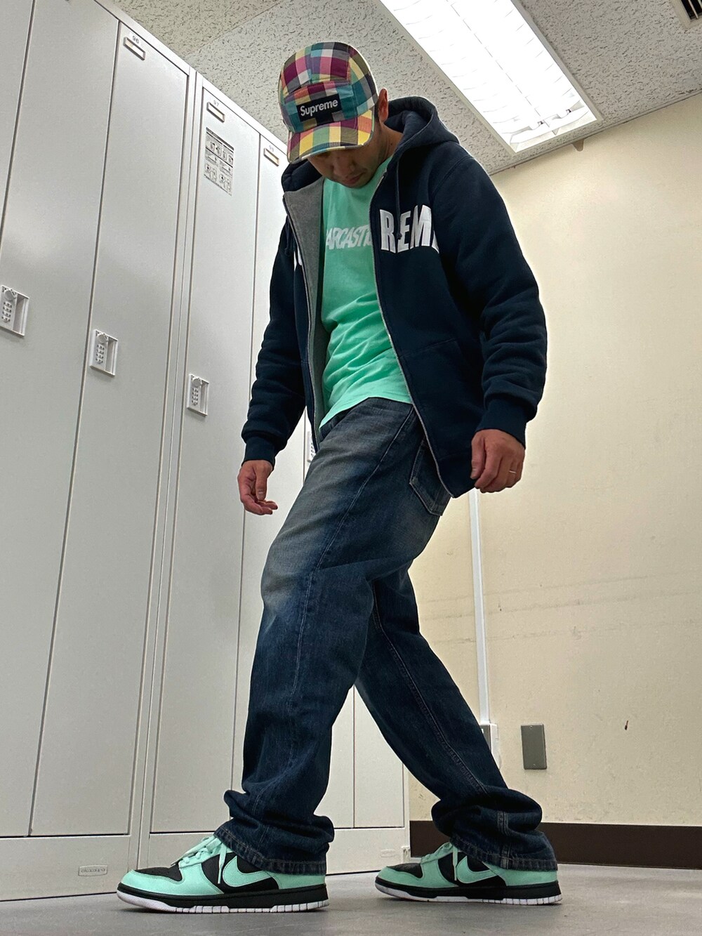 グリーン系のTシャツ/カットソー、ブルー系のパーカー、ブルー系のデニムパンツを着用したメンズの春コーディネートの2枚目の写真