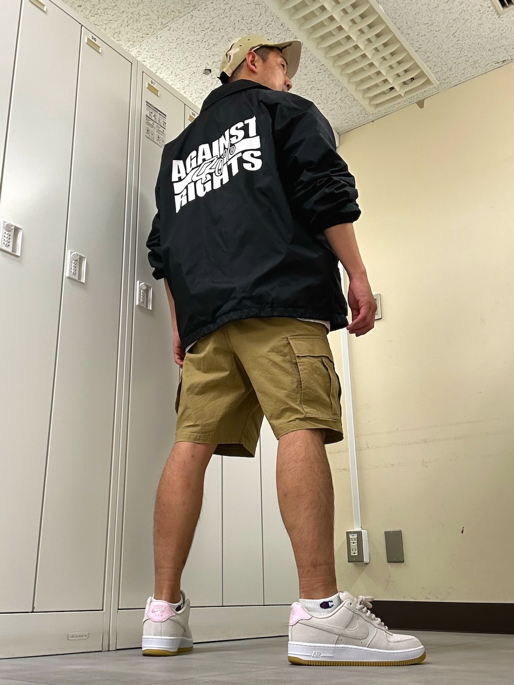 ブラック系のナイロンジャケット、ベージュ系のカーゴパンツ、ベージュ系のスニーカーを着用したメンズの春コーディネートの3枚目の写真