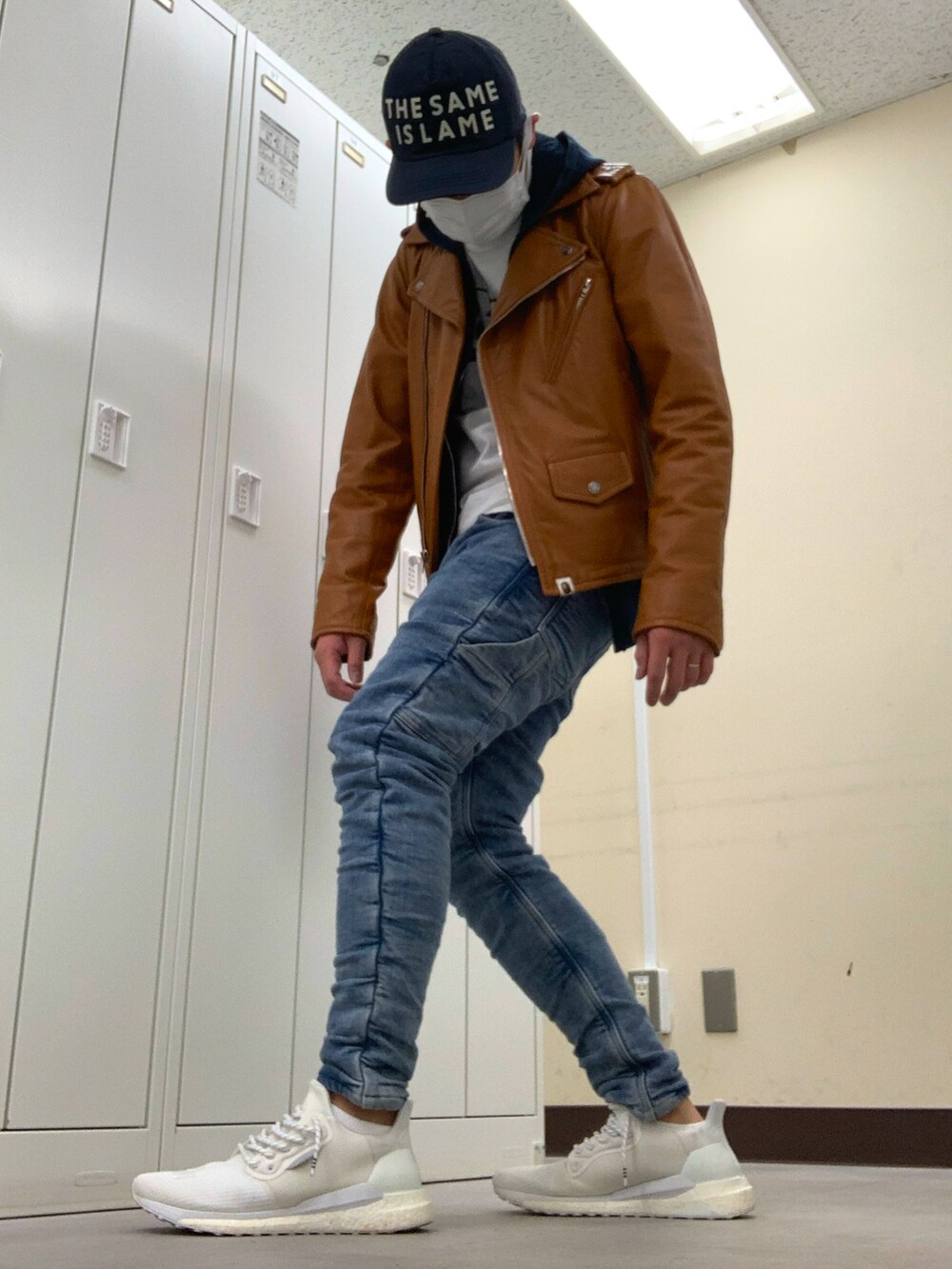 ブラウン系のライダースジャケット、ブルー系のデニムパンツ、ホワイト系のスニーカーを着用したメンズの春コーディネートの2枚目の写真