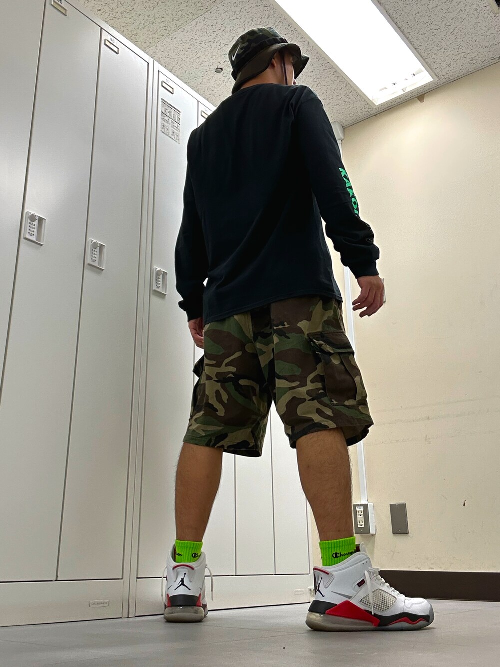 ブラック系のTシャツ/カットソー、グリーン系のカーゴパンツ、ホワイト系のスニーカーを着用したメンズの秋コーディネートの3枚目の写真