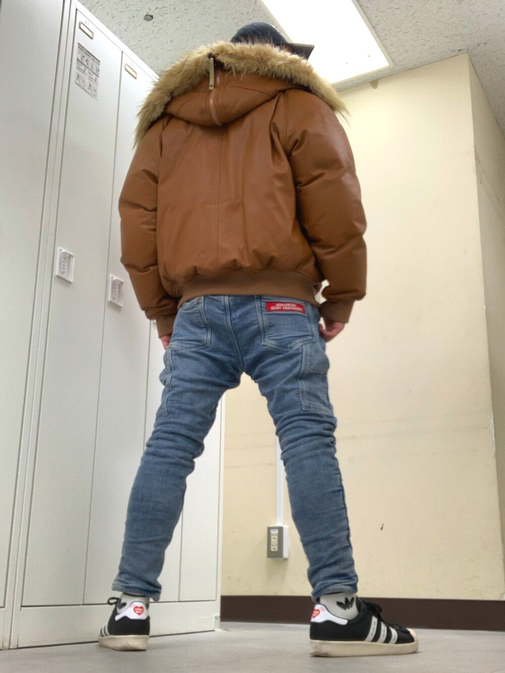 ブラウン系のジャケット/アウター、ブルー系のデニムパンツ、ブラック系のスニーカーを着用したメンズの冬コーディネートの2枚目の写真