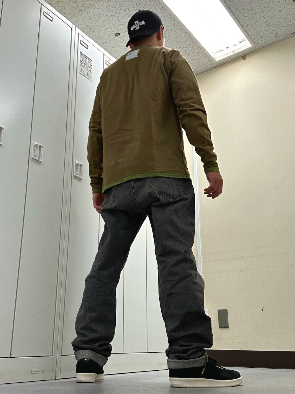 グリーン系のTシャツ/カットソー、グレー系のデニムパンツ、ブラック系のスニーカーを着用したメンズの秋コーディネートの3枚目の写真
