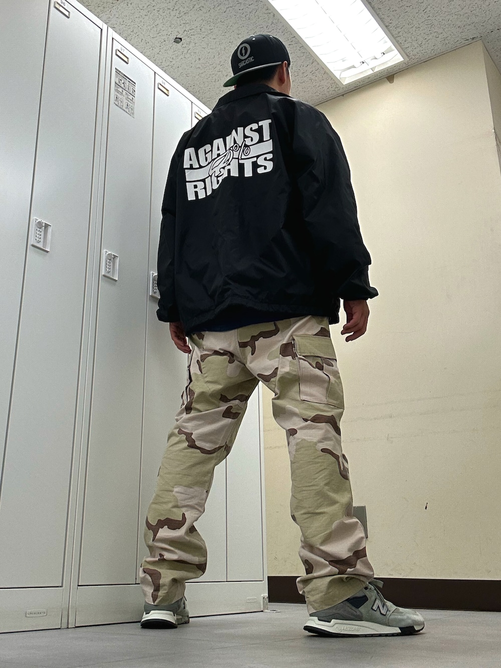 ブラック系のナイロンジャケット、ベージュ系のカーゴパンツ、グレー系のスニーカーを着用したメンズの春コーディネートの3枚目の写真