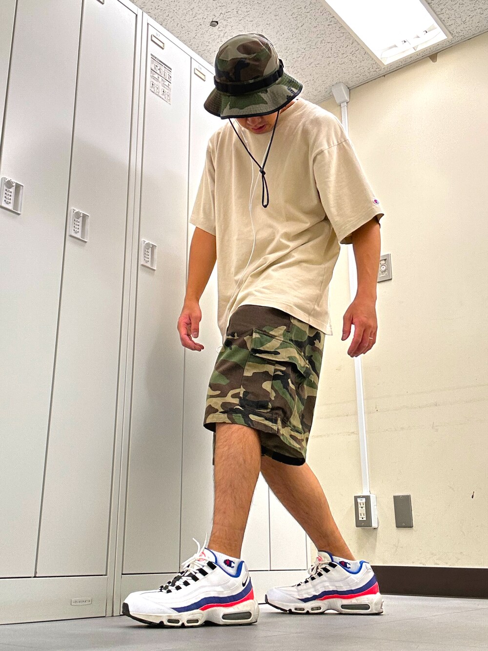 ベージュ系のTシャツ/カットソー、グリーン系のカーゴパンツ、ホワイト系のスニーカーを着用したメンズの夏コーディネートの2枚目の写真