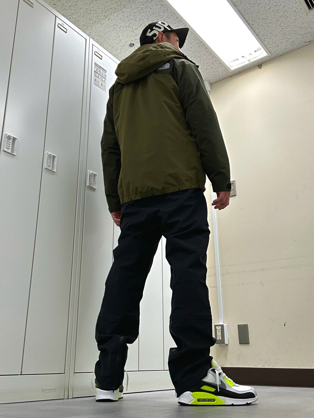 グリーン系のマウンテンパーカー、ブラック系のその他パンツ、ホワイト系のスニーカーを着用したメンズの秋コーディネートの3枚目の写真